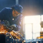 A person wears protective gear while working with metal