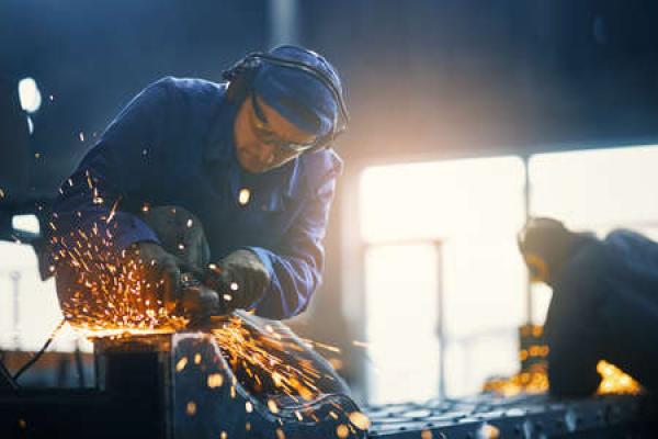 A person wears protective gear while working with metal