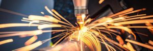 A CNC laser cutting through a metal pipe