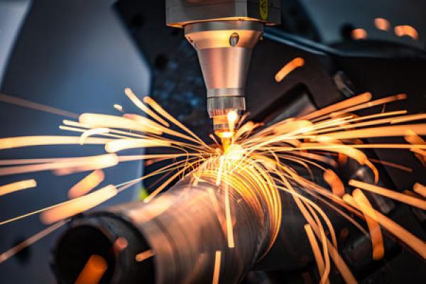 A CNC laser cutting through a metal pipe