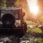 A Jeep drives through a muddy terrain